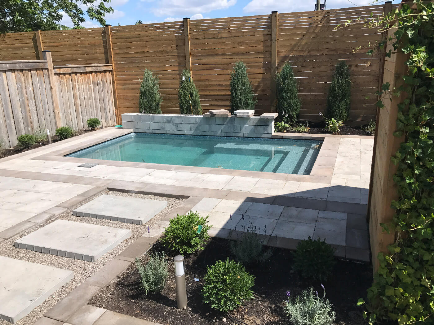Stone patio installed around saltwater swimming pool built by Seaway Pools & Hot Tub designers.