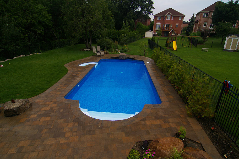 Pool installation with stonework and patio furniture by Seaway Pools