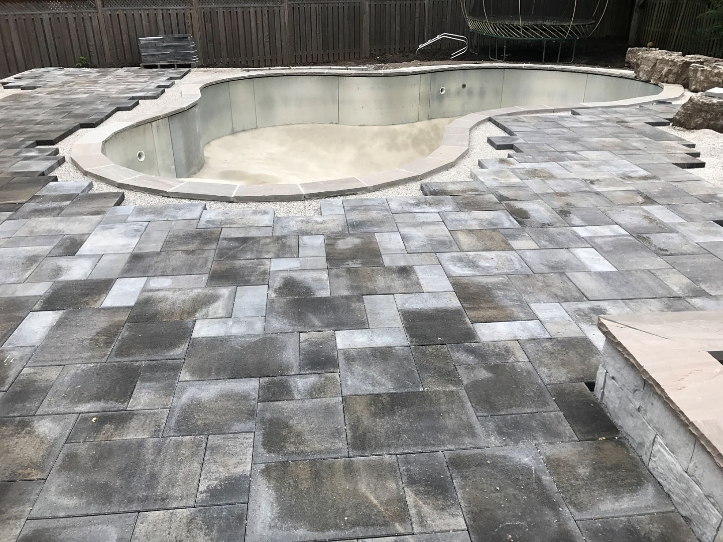 Custom stonework patio around swimming pool renovation